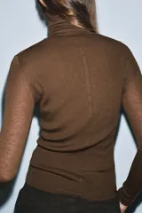 Jersey de punto con lana, de cuello subido y manga larga. Presenta un diseño ajustado con detalle de costuras verticales marcadas en el frente.