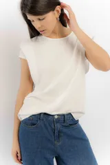Remera básica de color crudo con cuello redondo y mangas con detalle de hombreras sutiles que le dan estructura. Confeccionada en una mezcla de tencel y lino, ofrece una caída suave y un estilo versátil para uso diario.