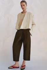 Pantalón cropped de tiro medio con diseño de pinzas en el delantero, trabillas para cinturón, bolsillos laterales y bolsillos de vivo en la parte trasera. Cierre frontal con cremallera y botón.