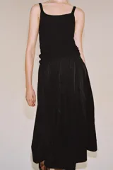 Falda midi de tiro medio color negro, con cintura elástica, bolsillos laterales ocultos y bajo con acabado en línea evasé.