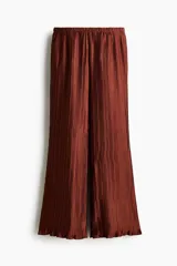 Pantalón wide leg marrón de tejido plisado con ligero brillo, cintura elástica y bolsillos laterales al bies.