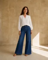 Camisa blanca de manga larga con detalles de encaje, pliegues frontales y cuello con volados.