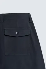 Pantalón de corte balloon fit, color negro, con bolsillos laterales de vivo y bolsillos traseros con solapa. Presenta cierre frontal con cremallera y botón.