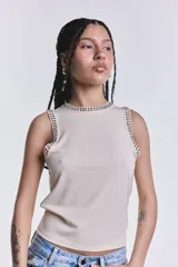 Musculosa color crudo de tejido estriado, con cuello redondo y sisas decoradas con tachas metálicas plateadas.