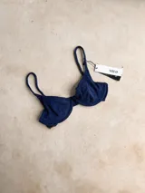 Top de bikini con aro, confeccionado en tela con acabado brillante. Presenta breteles regulables y cierre mediante atadura en la espalda.