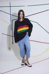 Sweater tejido de lana color negro con rayas horizontales en rojo, amarillo y verde. De corte holgado y mangas largas.