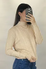 Buzo de hilo de punto con diseño de trenzas verticales, cuello alto y cadena metálica decorativa incorporada en la parte frontal.