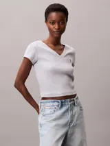 Remera de corte slim confeccionada en punto de algodón elástico con textura de canalé fino. Presenta cuello en V, manga corta y una insignia con el logo de Calvin Klein en el pecho.