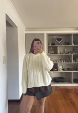 Buzo tejido de punto con diseño de trenzas verticales, cuello redondo y mangas largas con puños acanalados.