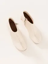 Bota de cuero color blanco con taco acrílico transparente y cierre lateral.
