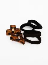 Set de accesorios para el cabello compuesto por dos broches tipo clip de carey y dos gomitas elásticas en colores negro y marrón.