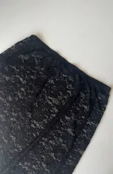 Pollera larga de encaje negro con abertura frontal y cintura elastizada.