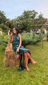 Top de fiesta color verde azulado iridiscente, con escote halter y frunces drapeados en el frente. Presenta un vivo de color naranja rojizo en el borde del escote y tiras para anudar en la espalda.