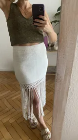 Falda tejida a mano en crochet, color crudo, con flecos en el ruedo y abertura lateral.