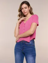 Cardigan corto fucsia de tejido de punto fino con hilo brillante de lurex, escote en V pronunciado y cierre frontal de botones a tono. Presenta mangas cortas y ruedo con corte en pico en el frente.