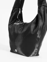 Bolso tipo hobo de color negro con acabado satinado y estructura blanda. Cuenta con un asa corta integrada, cierre superior y un llavero decorativo con temática de tenis colgando del tirador del cierre.