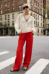 Blusa blanca de manga larga y escote en V, con detalles de crochet en el pecho y puños.