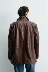 Blazer de corte relajado confeccionada en piel con acabado napado, cuello con solapas de muesca, manga larga, bolsillos frontales de plastrón y cierre frontal de botonadura.