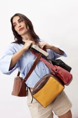Bandolera semirrígida Sagali de cuero vacuno color bordó, con textura de cocodrilo en el bolsillo frontal y cuerpo liso. Cuenta con cierre superior y correa regulable.
