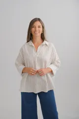 Blusa de corte holgado con estampado de rayas verticales en tonos beige y blanco. Presenta cuello camisero con escote en V, mangas largas con puños anchos y dobladillo redondeado.