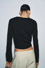 Chaqueta de punto liso color blanco, con cuello redondo, manga larga acabada con cremalleras en los puños y cierre frontal con cremallera.