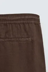 Bermuda de algodón color beige claro, de corte regular fit, con cintura elástica ajustable mediante cordón. Presenta bolsillos laterales y un bolsillo trasero de vivo.