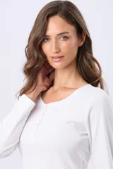 Remera lisa de algodón color blanco, con cuello redondo y botones a tono. Tiene manga larga y un ruedo curvo.