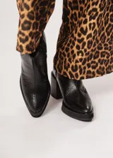 Botín negro de cuero con elástico lateral y cierre interno. Tiene plataforma delantera de 2 cm y taco de 8 cm.