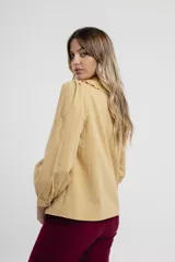 Camisa verde agua con cuello babero con volados, mangas largas abullonadas y cierre frontal con botones.