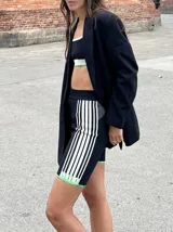 Calza corta de lycra negra con rayas verticales blancas y terminaciones en verde flúor.