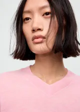 Jersey de punto fino color rosado, con cuello en V, manga larga y diseño recto.