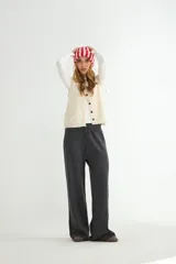 Pantalón de punto color crema, de corte recto y holgado, con cintura elástica y cordón ajustable. Presenta costuras verticales decorativas a lo largo de las piernas.