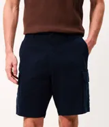 Bermuda de sarga negra de corte recto y holgado para hombre, con bolsillos cargo laterales con solapa, cintura con pasadores y cierre frontal con botón y cremallera.