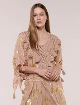 Blusa holgada de gasa color rosa con estampado metalizado dorado, escote en V con pechera tejida en crochet y apliques de borlas.