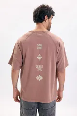 Remera de manga corta raglán en color marrón, de corte holgado y diseño liso con estampado tipográfico y gráfico en la espalda.