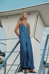 Mono largo fluido de mezcla de lyocell en color azul, con escote en V, tirantes finos tipo halter y piernas amplias con puños elásticos en los tobillos.