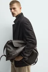 Blazer de corte relajado confeccionada en piel con acabado de ante. Presenta cuello con solapas de muesca, cierre frontal de dos botones, mangas largas y bolsillos de plastrón en la parte delantera. Destaca por sus costuras con efecto lavado que le otorgan un aspecto vintage.