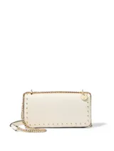 Bolso cruzado City Mini de color blanco marfil, con detalles de tachas doradas a lo largo de los bordes y correa de cadena metálica dorada. Cuenta con solapa frontal y cierre magnético.