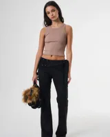 Pantalon negro de corte recto y tiro bajo, con detalle de cintura solapada decorada con tachas metálicas y lazo lateral para ajuste.