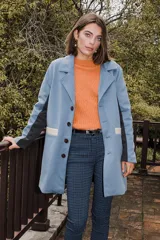 Tapado azul con solapas, cierre con botones, mangas largas con detalle de franja gris y bolsillos con ribete color crema.