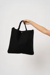 Bolso tipo tote bag negro con asas cortas y cierre con botón a presión.
