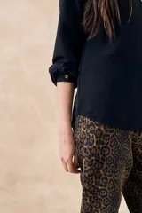 Blusa negra con cuello mao, calce al cuerpo y mangas 3/4 con puños abotonados. Cierre frontal con botones.