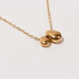 Collar dorado con cadena fina y dije de dos piedras irregulares.