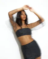 Vestido corto de red con brillos, mangas largas y cuello redondo. Incluye top y short negro.