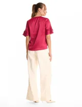 Blusa de satén color verde oliva, con cuello redondo y escote en V. Presenta mangas cortas con tres capas de volados superpuestos.