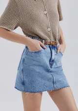 Minifalda de jean azul con bolsillos delanteros y traseros, corte recto y ruedo desflecado.