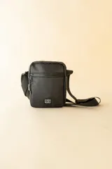 Bandolera negra con correa ajustable y logo de la marca Rusty en el frente.