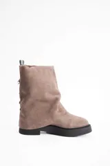 Bota de caña media confeccionada en cuero vacuno color marrón oscuro, con diseño de pliegues en la caña y suela de goma al tono con textura estriada.