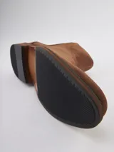 Bota Chelsea de gamuza gris con elásticos laterales, suela de goma marrón y tirador trasero.