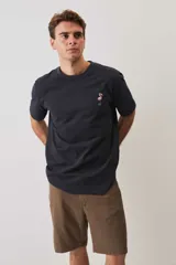 Remera blanca de manga corta y corte holgado, con cuello redondo y pequeño estampado en el pecho.